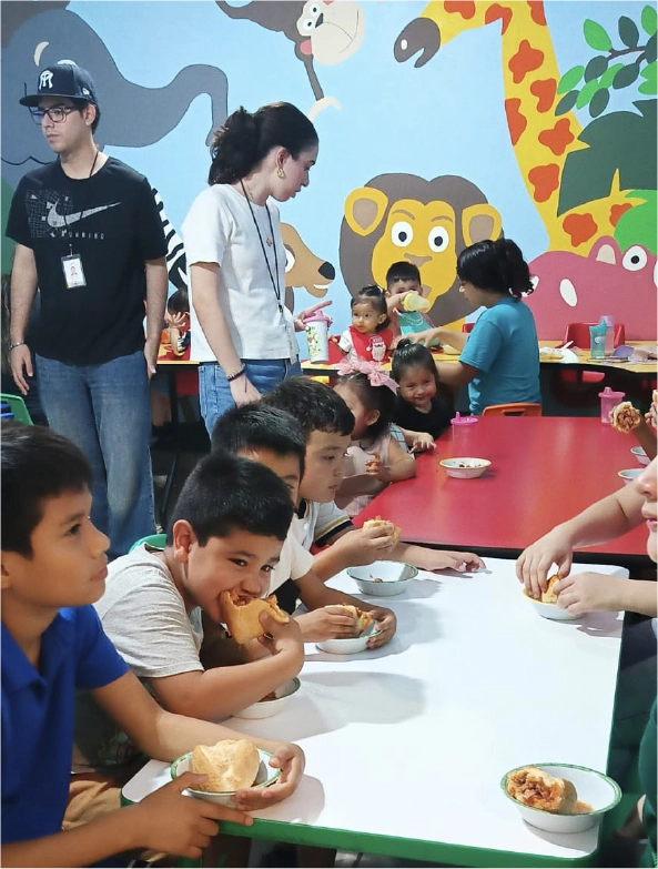Colaboradora de CAYAM acompañando a un grupo de niños en el comedor escolar.