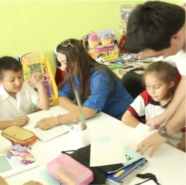 Colaboradores y niños realizando actividades de aprendizaje en el aula.