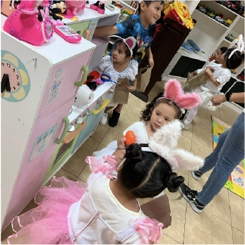 Personal educativo de CAYAM interactuando con niños en un aula decorada con murales de animales.