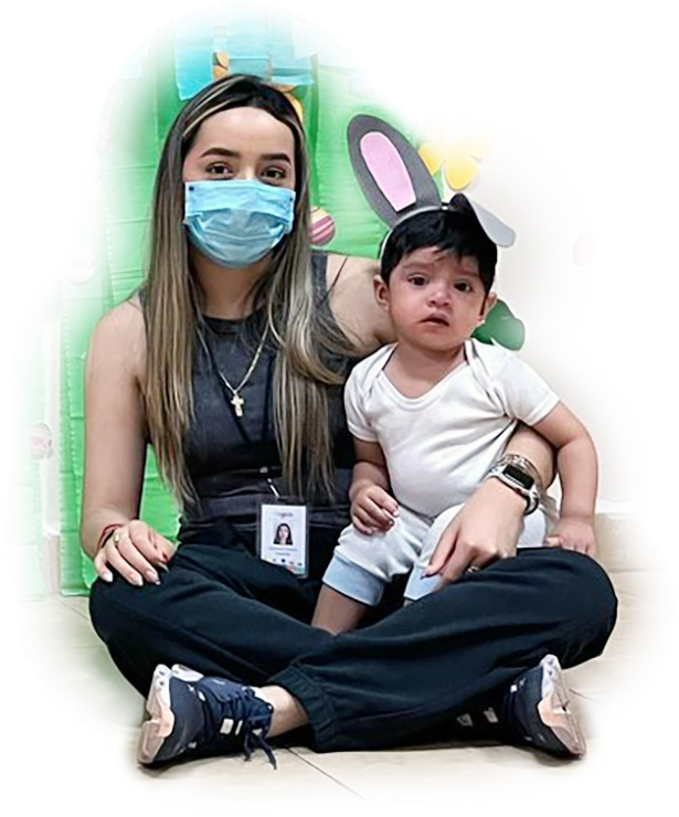 Maestra de CAYAM sentada con un niño pequeño en brazos, representando el cuidado y la atención personalizada del centro.